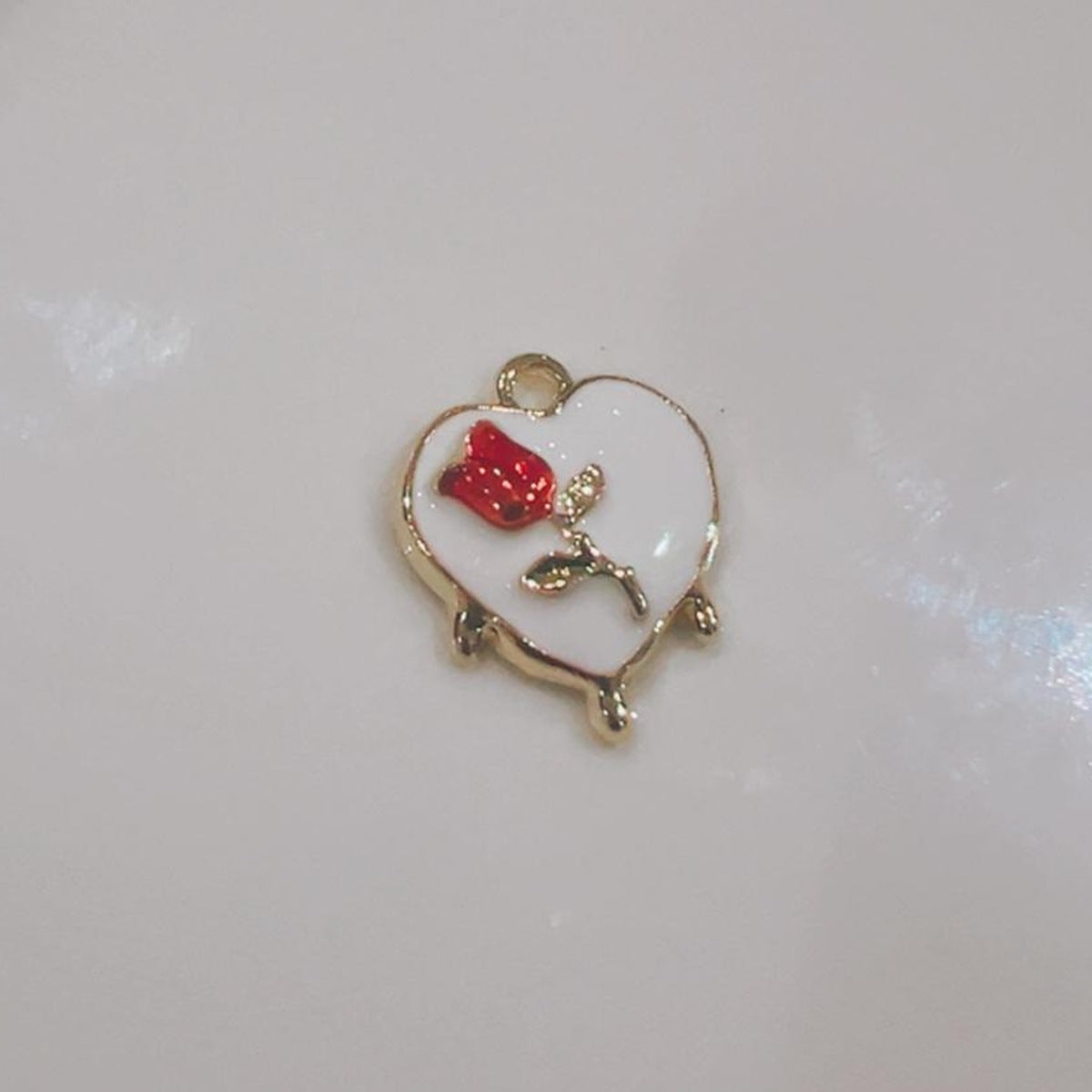 White heart charm with a red flower on a white background