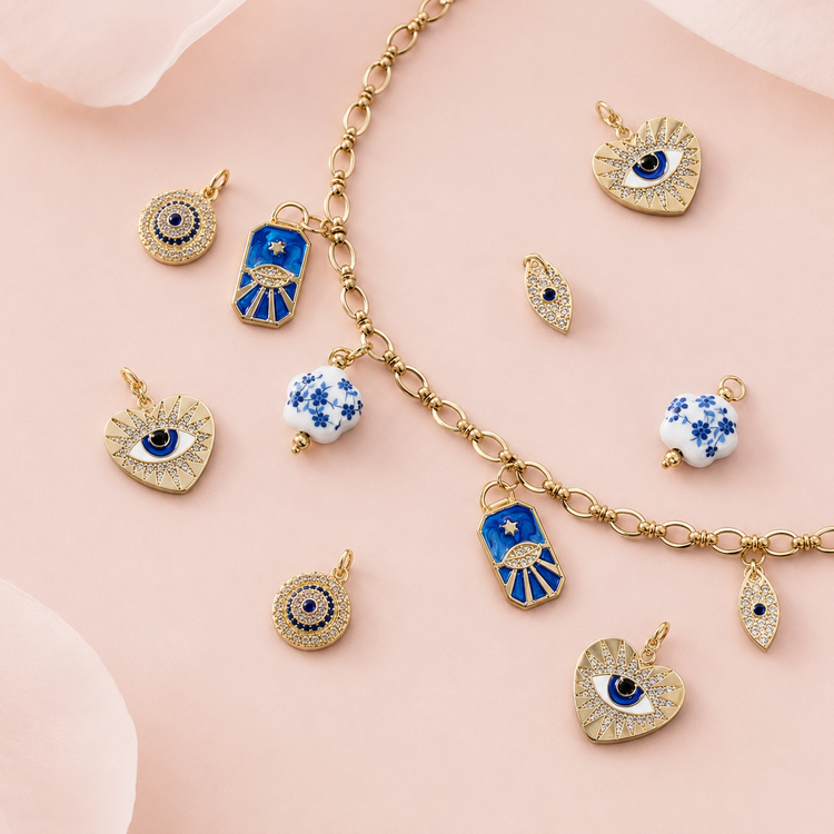 Gold and blue evil eye charms for personalised charm jewellery on a soft pink background