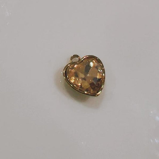 Amber crystal heart charm with a gold-coloured frame on a white background