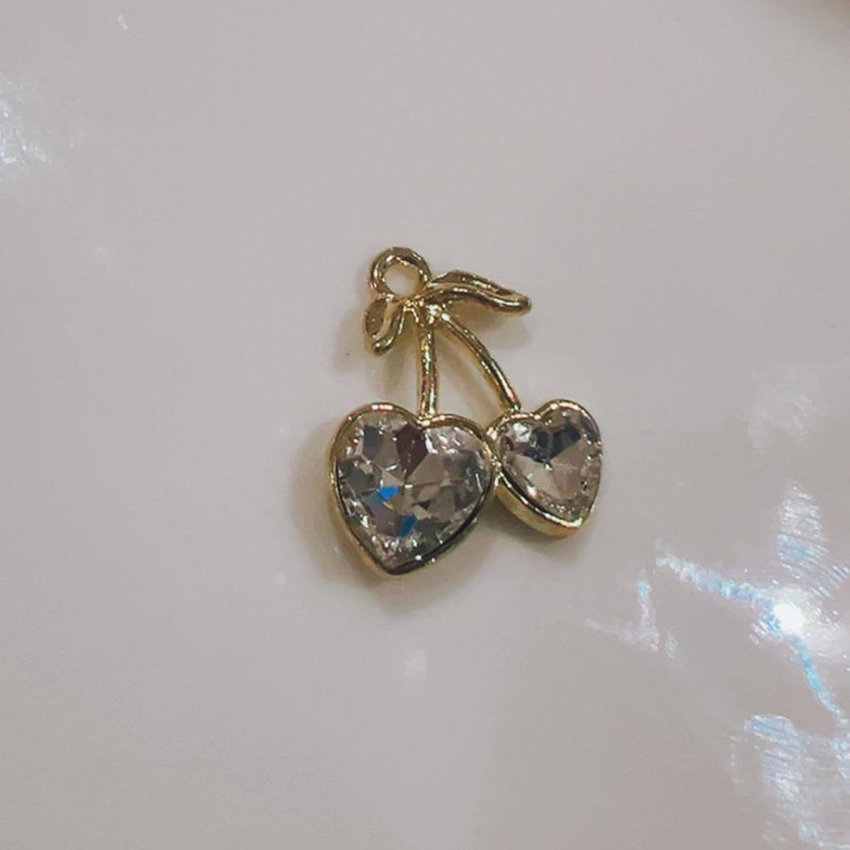 Clear cherry hearts charm with two clear hearts and a green leaf on a white background