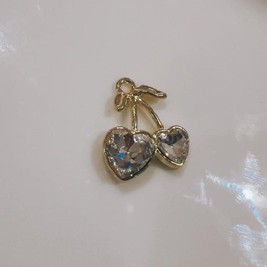 Clear cherry hearts charm with two clear hearts and a green leaf on a white background
