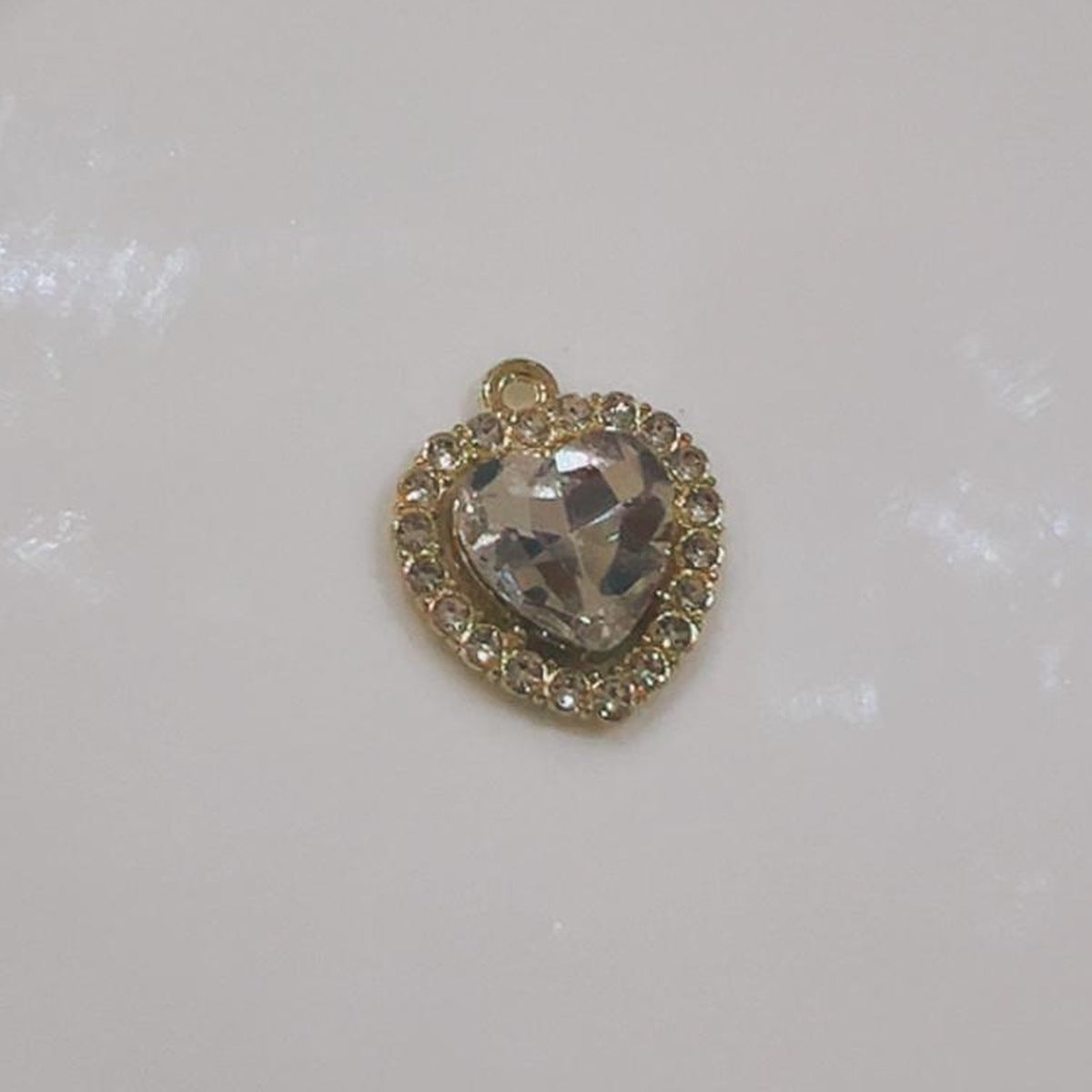 Clear crystal heart charm with a sparkling border on a white background