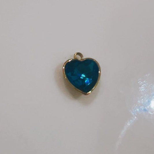 Deep teal faceted heart charm on a white background