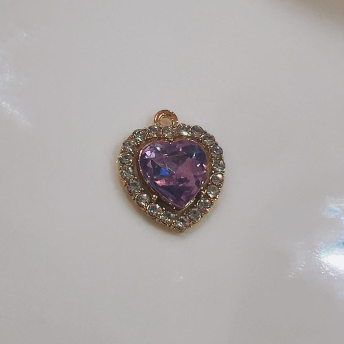 Purple heart charm with a sparkling crystal edge on a white background